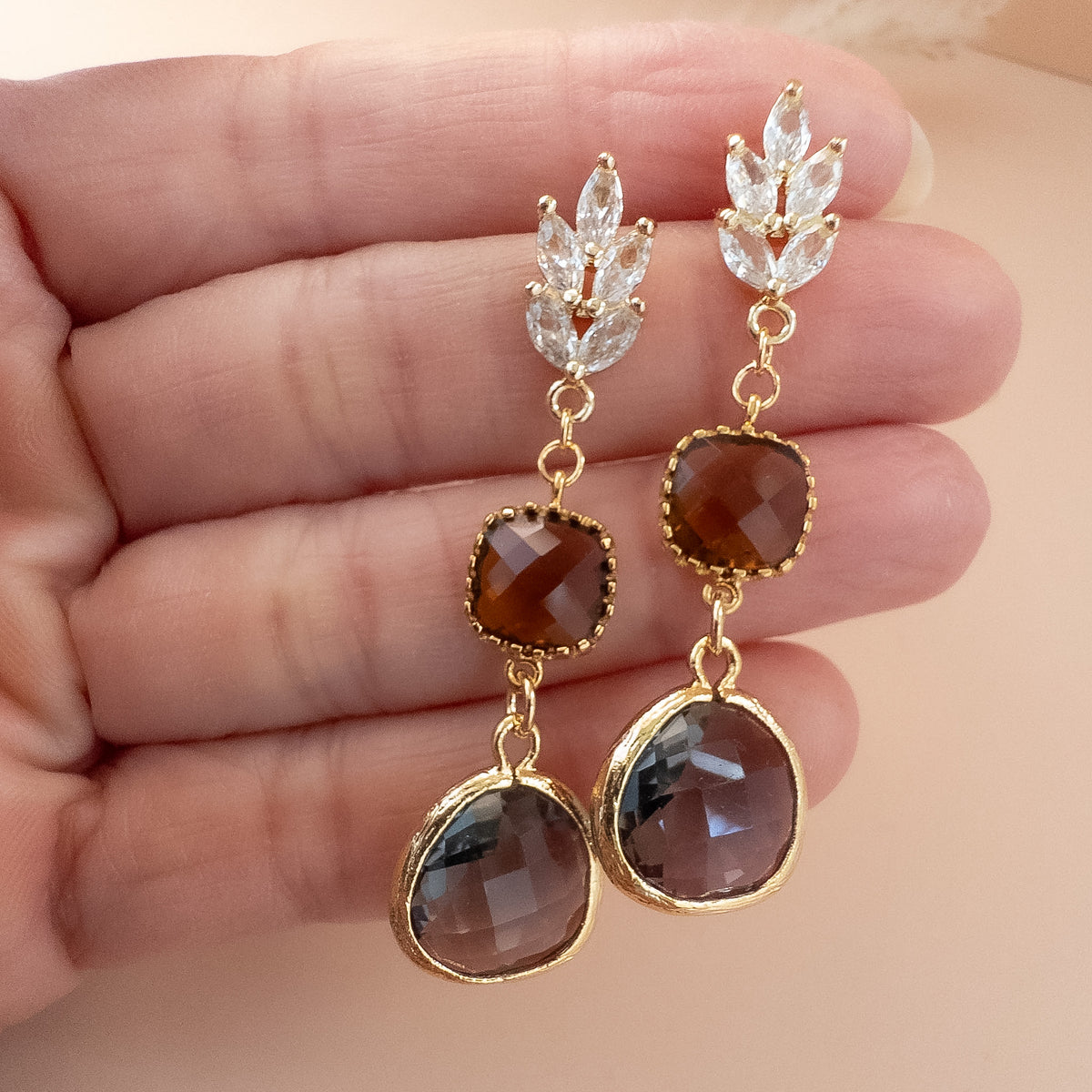 Leaf stud drop earrings held in palm to show length and size
