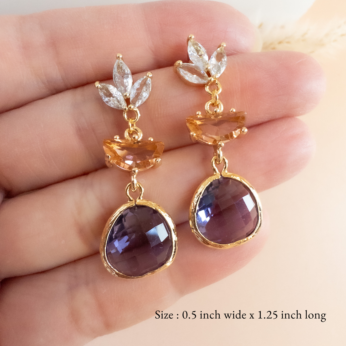 Peach and plum crystal drop earrings held in hand to show size