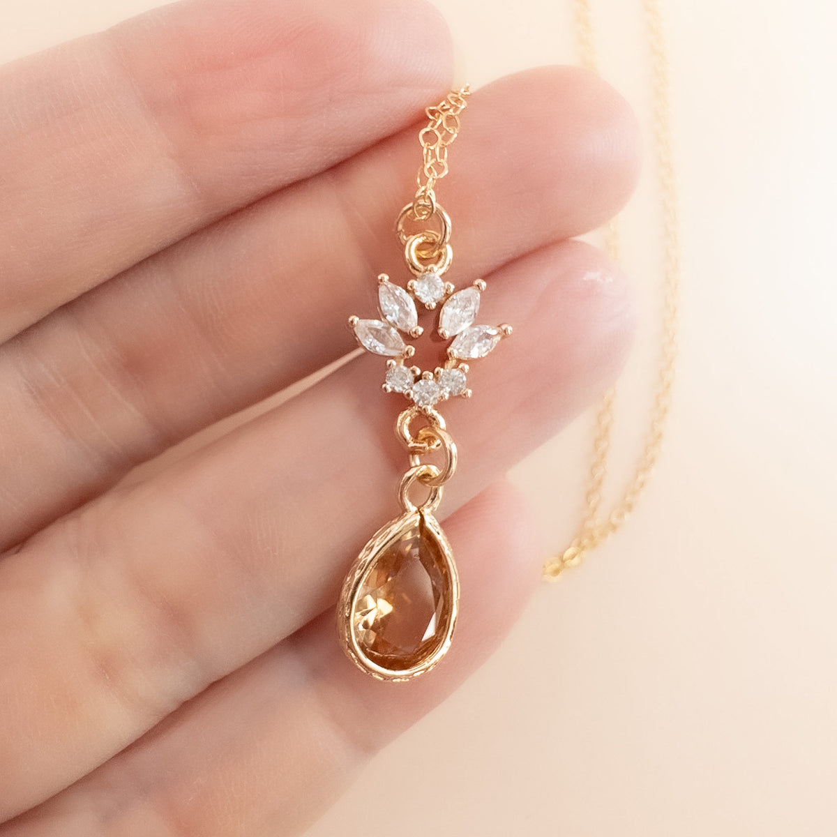 a hand holding the champagne stone pendant