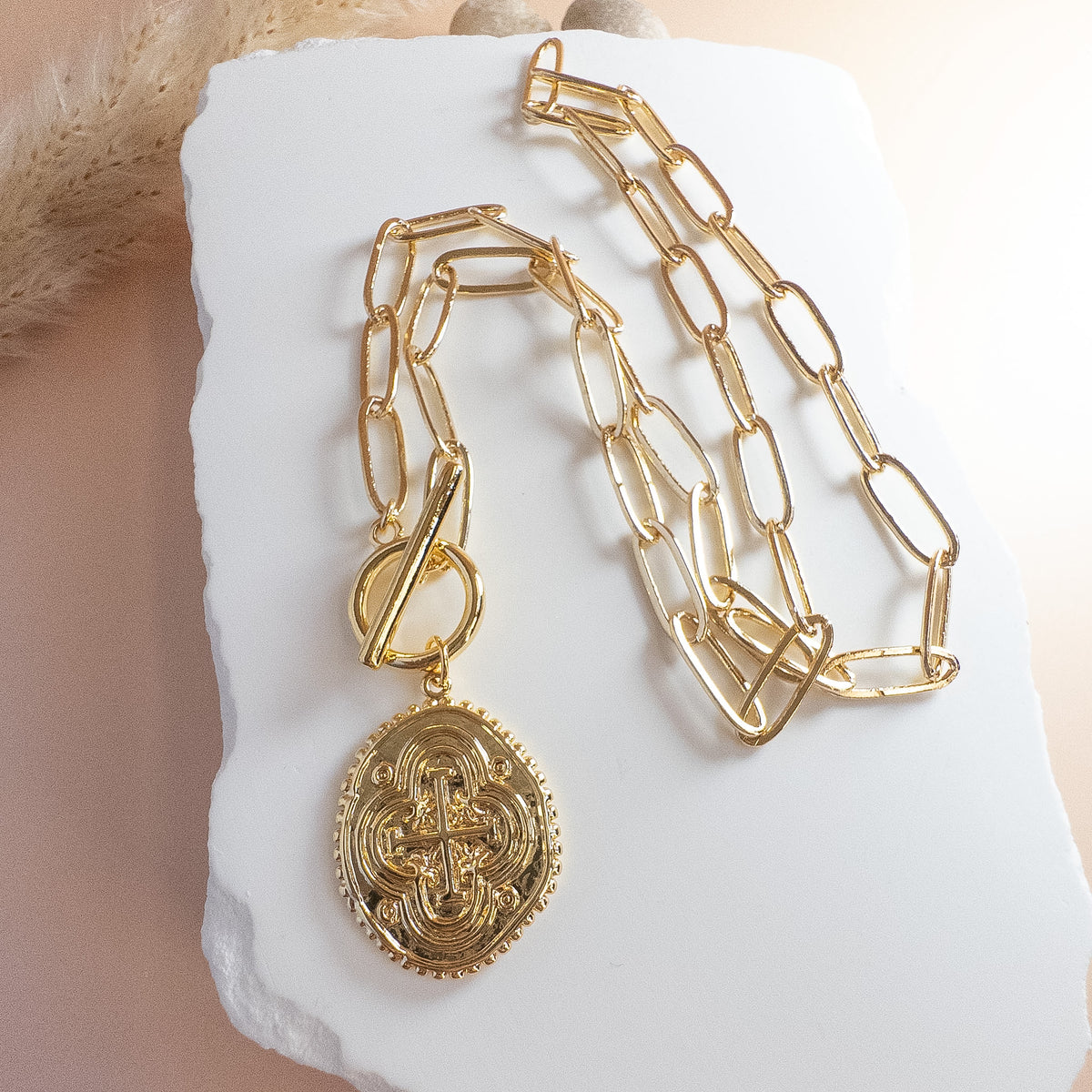 vintage style gold medallion with cross  designs, displayed on white stone