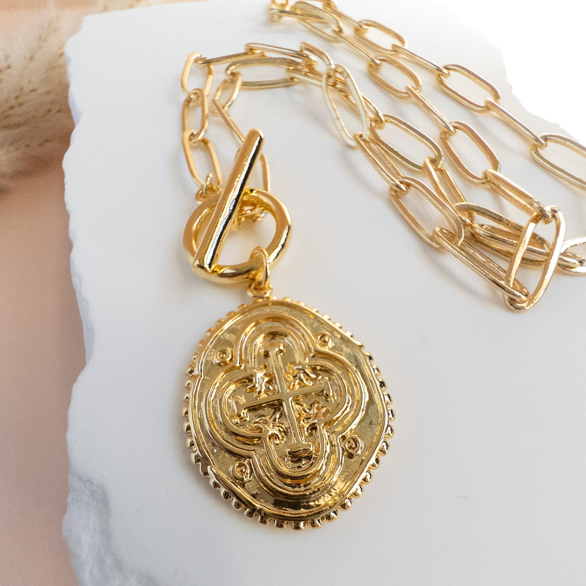 close up of vintage style medallion with cross and quatrefoil designs and toggle clasp