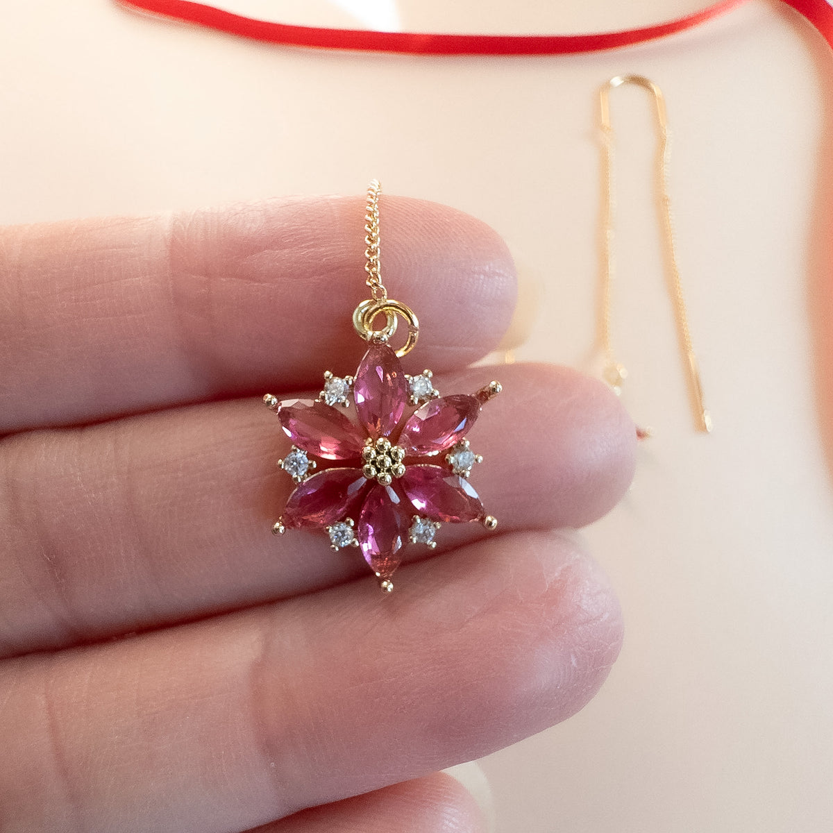 Poinsettia charm held between fingers to show size