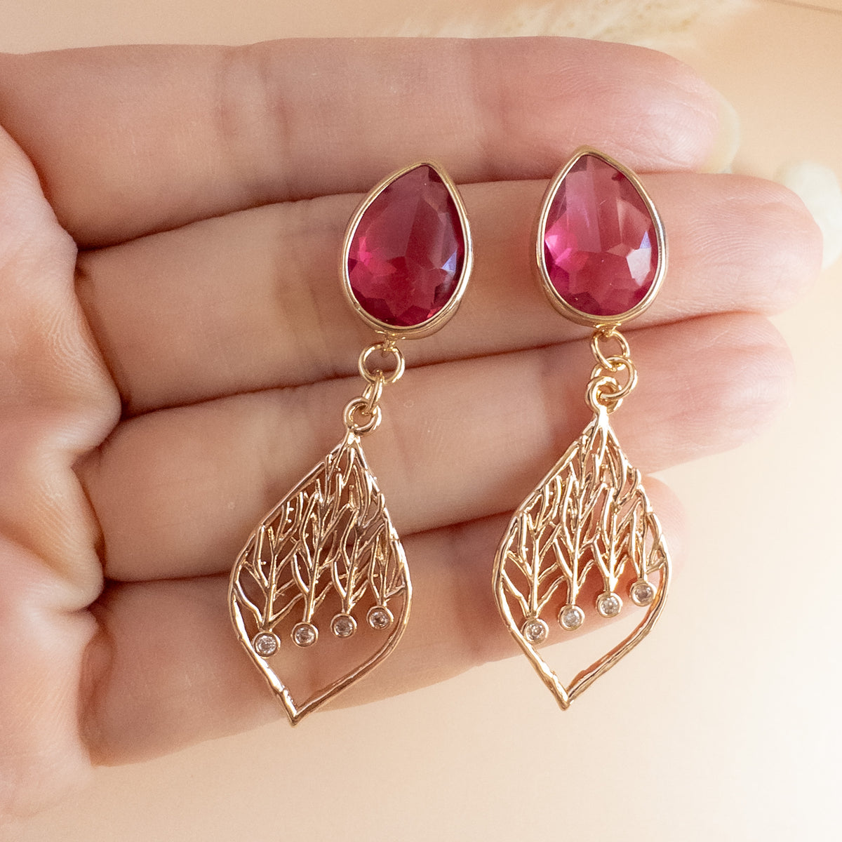 Raspberry teardrop leaf earrings held in hand to show size