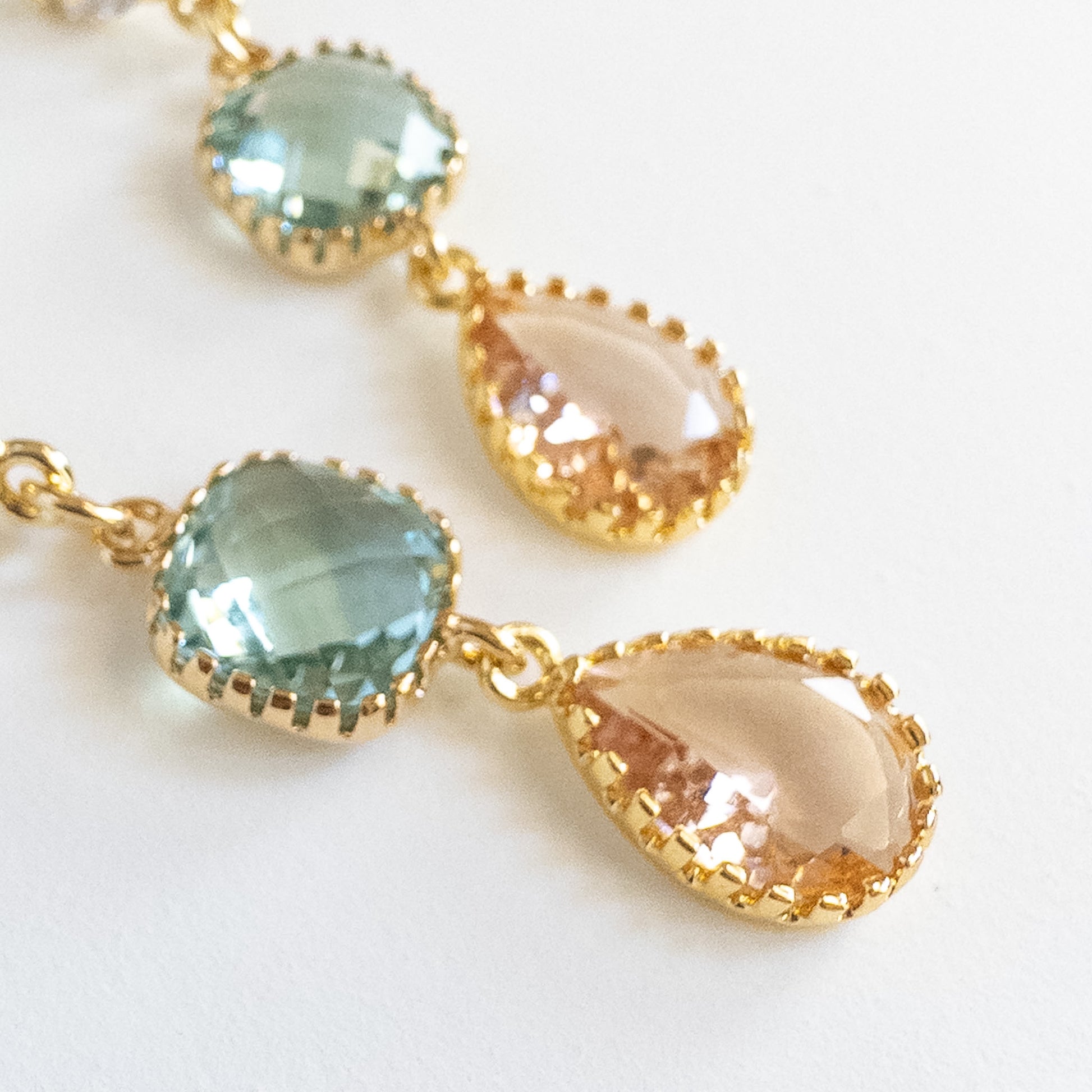 Close-up of gold-plated seafoam and peach teardrop crystal earrings