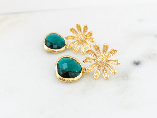 Gold daisy post earrings with emerald green crystal stones laying flat on a white surface. earrings by YSM Designs