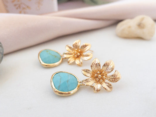 Gold Flower post earrings with turquoise stones laying flat on a white surface. Gold earrings by YSM designs